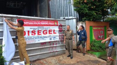 Satpol PP Kota Tangerang Selatan membuka segel yang ditutup kain pada pembangunan pabrik masker di Pondok Aren