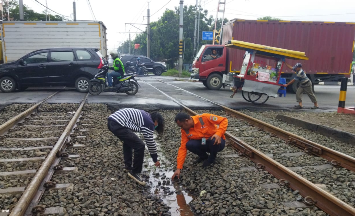 Penjaga perlintasan kereta api menunjukkan JDU pipa air milik Perumda TKR yang bocor